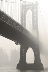 Fototapeta premium Bridge over a lake or river, city skyline in the background, calm waters vertical frame