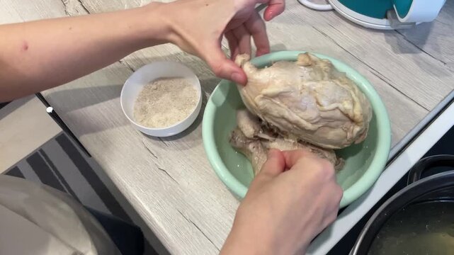 raw chicken stuffed with rice, hands placing grains into cavity over green bowl, closeup top view of kitchen counter, stepbystep home cooking scene, prep for oven roast, neutral lighting