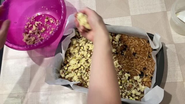 caucasian cook assembling streusel topping layer over pastry base, hands breaking and scattering chunky crumbs across surface, purple bowl emptied and set aside, rustic homemade vibe and careful