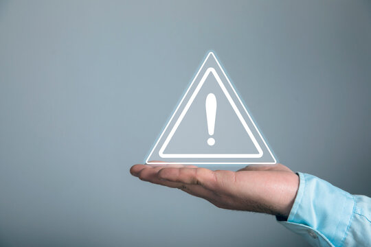 A young man clicks on a virtual screen with a warning sign.