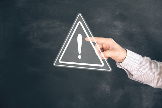 A young man clicks on a virtual screen with a warning sign.