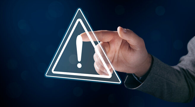 A young man clicks on a virtual screen with a warning sign.