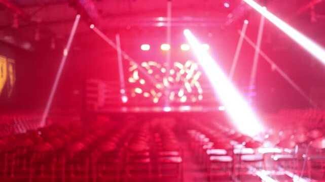 Empty boxing ring and rows of chairs under dramatic red stage lighting at event
