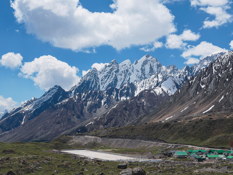 Panch Pandav Parvat mountain range near Adi Kailash in Uttarakhand, India, with snow-covered Himalayan peaks under a blue sky with clouds.