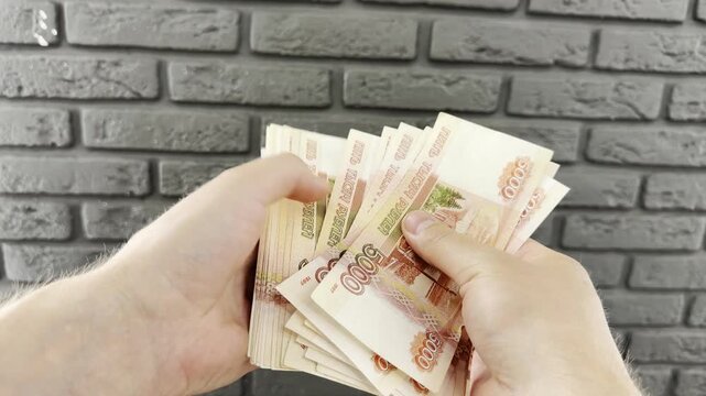 Man counts a bundle of bills for five  thousand Russian rubles at the workplace. Man counts paper, 5000 rubles bills. Russian cash money in male hand. A man holds a wad of money in his hands. Russian 