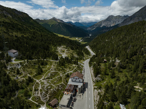 Aerial view of Fuorn Pass with a mountain hotel and a winding road through dense pine forests in the Swiss Alps Val Mustair, Grisons, Switzerland.