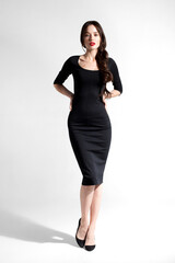 Fototapeta premium Woman posing in black dress standing on white studio backdrop
