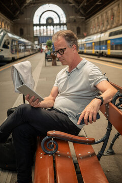 Mature businessman using tablet while waiting at railway station during travel