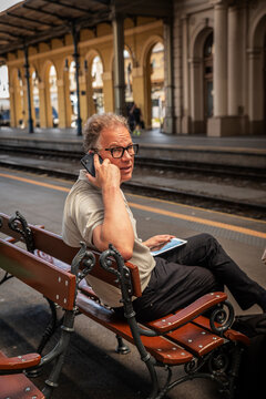 Mature businessman talking on smartphone while waiting at railway station