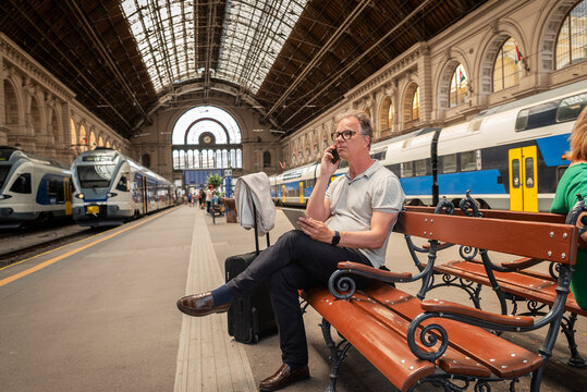 Mature businessman talking on smartphone while waiting at railway station