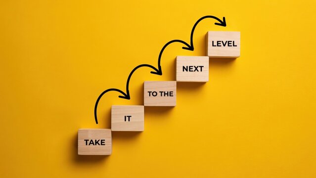 Wooden blocks with text take it to the next level arranged in stairs on yellow background