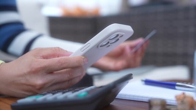 Personal budget planning and expense tracking using smartphone, calculator and handwritten notes. Managing household finances, monitoring spending, reviewing payments and organizing financial records.