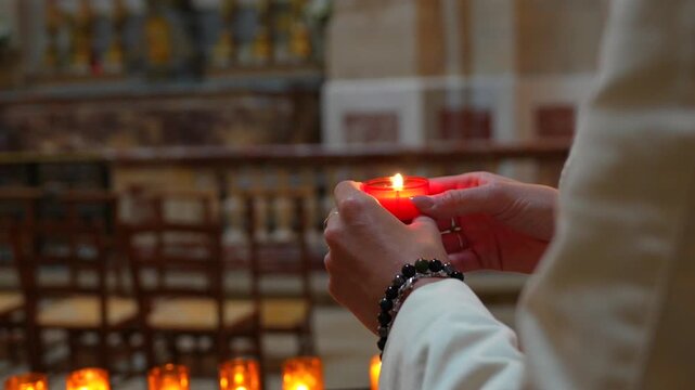Visitor holding a glowing devotional candle during Christian prayer
