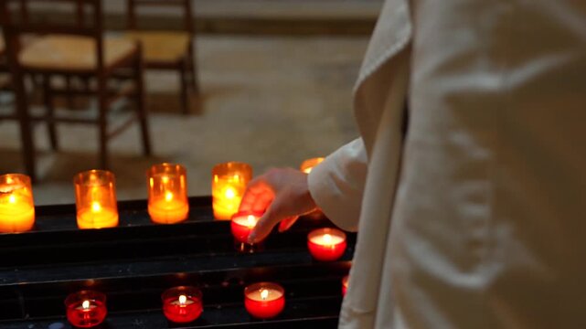 Visitor placing a glowing devotional candle during Christian prayer