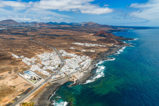 Aerial Panorama of La Santa Traditional White Fishing Village and Volcanic Rocky Coastline in Lanzarote