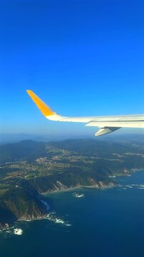 View of an airplane wing over a dramatic coastal landscape during flight