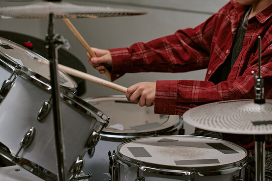 Teenager drummer playing drum kit during music practice, showing rhythm training and creative skill development. Useful for music education, youth programs, performance promotion
