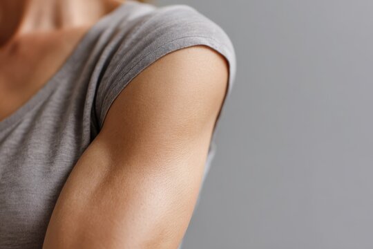 Close-up of a woman's upper arm showing sagging skin and natural texture under soft lighting