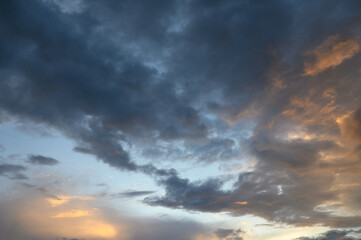 Fototapeta premium Evening cloudy skyline with sunset glow above urban horizon heavy clouds and bright city edge