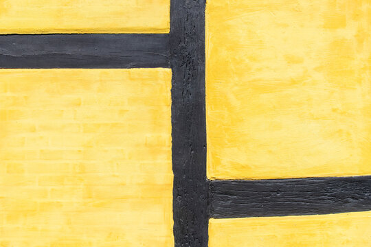 Close-up of traditional Danish half-timbered architecture (bindingsv&aelig;rk) with black wooden beams and yellow plaster wall in Copenhagen, Denmark with abstract geometric pattern