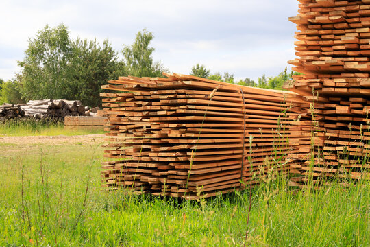 Stacks of sawn timber boards at open air lumberyard, packed wooden planks pile for construction material supply