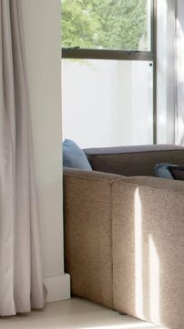 Vertical video: Panning camera revealing sofa in home corner to show blue pillow, lamp and window