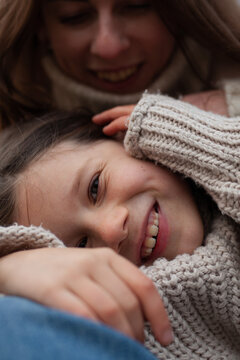Close-up portrait of happy mother and her daughter embracing, both wearing cozy knitted sweaters.Unconditional love, maternal bonding, family happiness, relaxed, heartwarming atmosphere.
