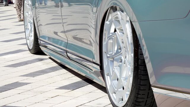 Close up of two wheels of extremely lowered car, rims tucked into fender arches, stance tuning
