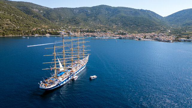 Aerial view of a large five-masted sailing ship with people on deck anchored in the blue waters of a bay near the town of Vis, Split-Dalmatia County, Croatia.