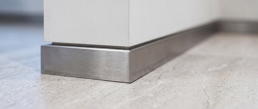 Stainless steel baseboard trim on tile floor corner modern interior detail and minimalist finish