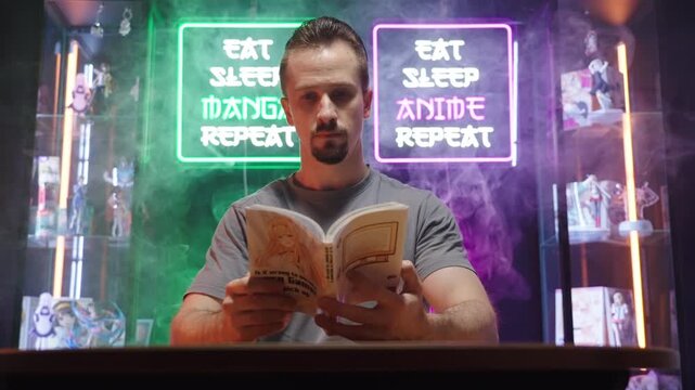 Man reading manga comic in cyberspace room with neon signs and merch showcases