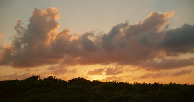 Golden sunset clouds rise above dense coastal jungle near Caribbean Tulum Mexico