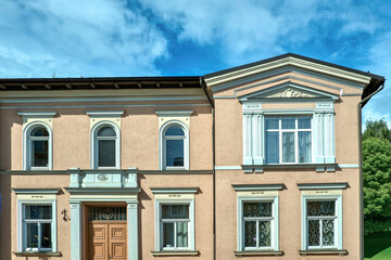 Obraz premium Facade of a classic European historic building with elegant windows, stucco details and peach-colored walls.