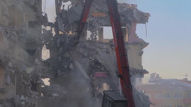 Excavator with hydraulic crusher is tearing down the old typical Turkish multi-storey apartment, residential building in Istanbul, Turkey - slow motion, demolition of building