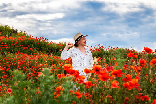 Elegant woman stands within blooming poppy meadow. Natural beauty, tranquil peaceful mindset.