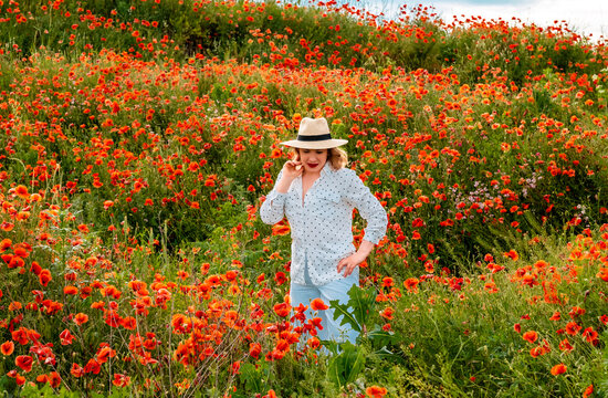 Composed woman pauses in endless floral field. Calm lifestyle, quiet relaxation concept.