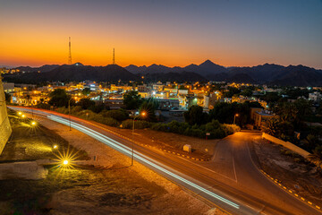 Long exposure night cityscape with car light trails and mountains at sunset © Diana Z