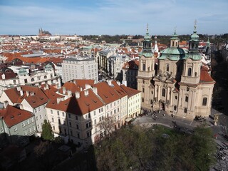 Obraz premium Aerial view of Prague: historic buildings with tiled roofs, Prague Castle, and city skyline on a clear sunny day. Landmarks and historic architecture of Prague, Czech Republic.