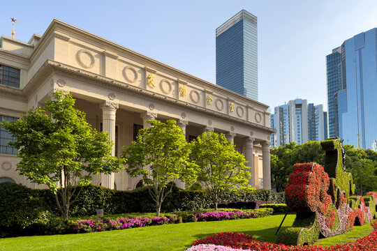 Neoclassical architecture of Shanghai Exhibition Center with manicured gardens and modern skyscrapers, China