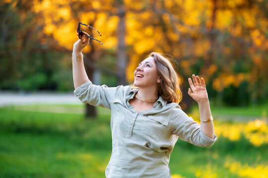 Joyful woman admires sunlight in scenic park. Pure happiness, radiant summer energy.