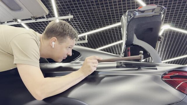 PDR. Paintless Car Dent Repair. Process of paintless dent repair on car body. The mechanic at the auto shop with tools to repair dents in car body. Body repair. A specialist repairs a dent on the car.