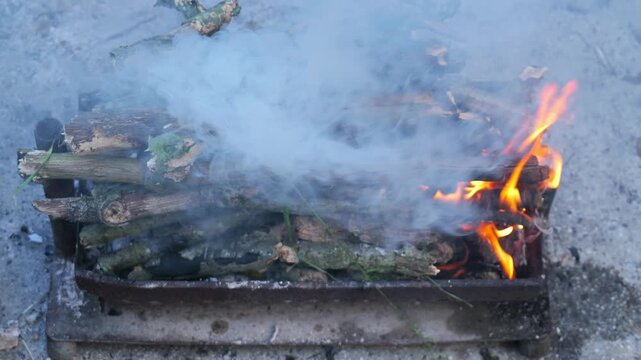 Burning firewood lighting up in a metal brazier outdoors