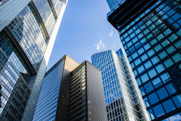 Fototapeta premium Modern skyscrapers with glass facades and reflective surfaces towering against a clear blue sky in an urban cityscape showcasing contemporary architecture