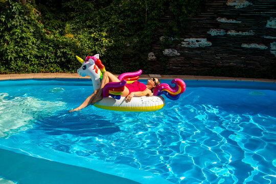 Woman on unicorn pool float in pool in hotel. Summer holidays, enjoying summer vacations