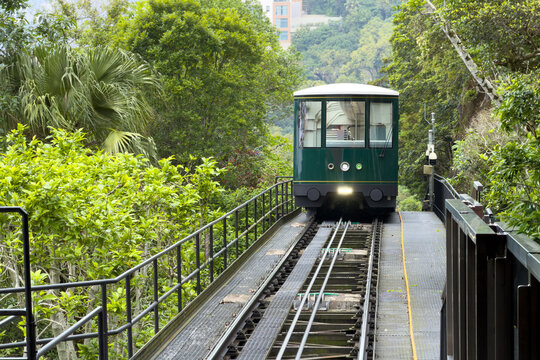 The iconic green Peak Tram funicular railway ascending through lush forest on Victoria Peak in Hong Kong