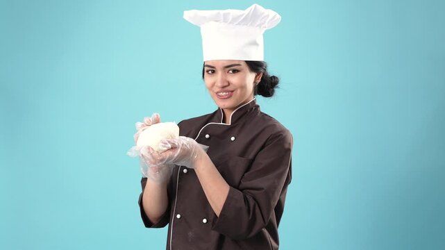 Happy female chef stretching fresh dough with hands