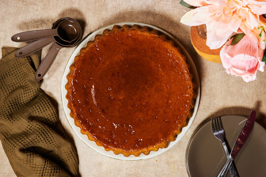 Glazed Gourmet baba au rhum cake on Plate With Measuring Spoons, Flowers and Cozy Table Setting