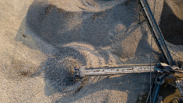 Aerial view of the Babakan industrial site featuring large piles of crushed gravel and a conveyor belt system in Karanglewas, Central Java, Indonesia.