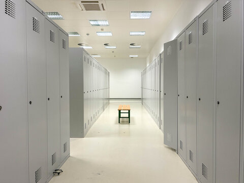 Rows of grey metal storage lockers in a spacious modern locker room, providing organized personal storage and changing facilities for staff in corporate or industrial environments
