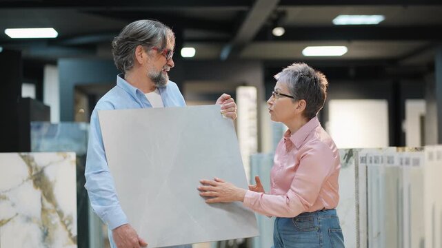 Senior couple choosing ceramic tile in hardware store showroom